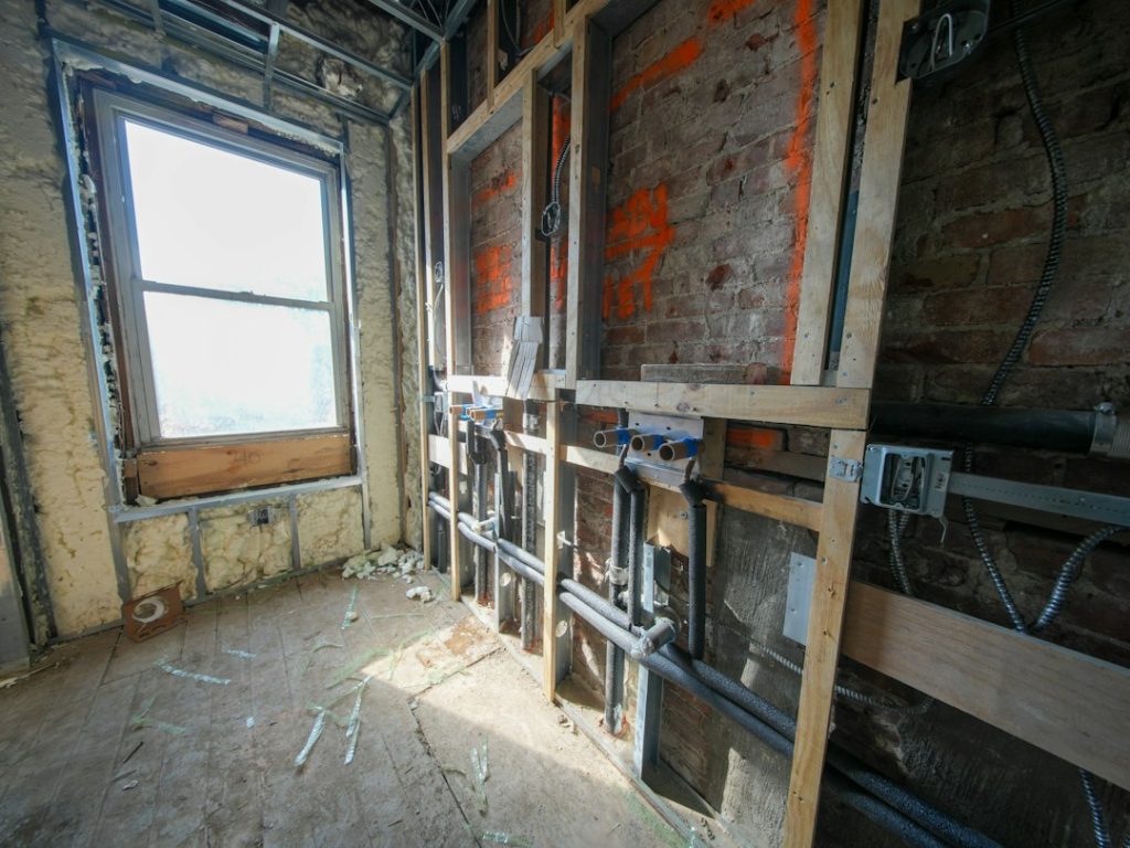 Interior room under construction with exposed pipes and wiring
